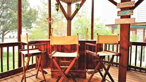 A wooden deck with four folding chairs, a wooden pergola, and a sign that reads "FLAMINGO Lounge".