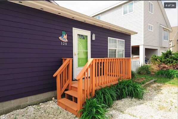 A house with a purple exterior, a wooden front porch, and a green door.