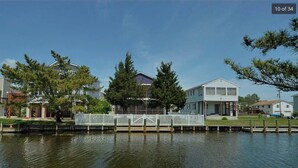 A waterfront property with a dock, a white fence, and a house with a porch.