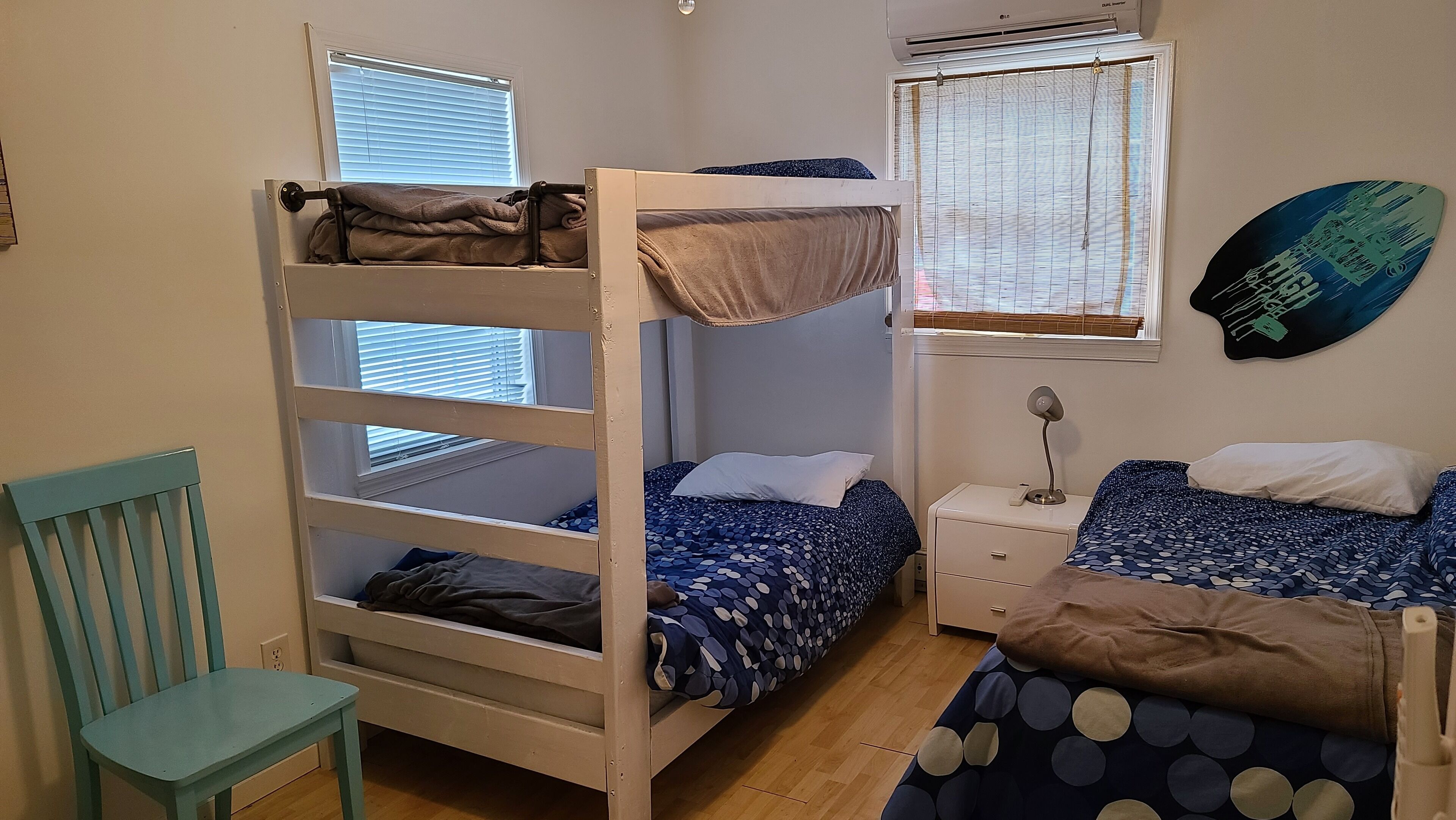 A bunk bed room with a desk, chair, and a wall-mounted fan.