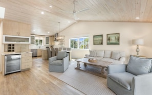 A spacious living area with a kitchen, dining area, and a large window providing natural light.