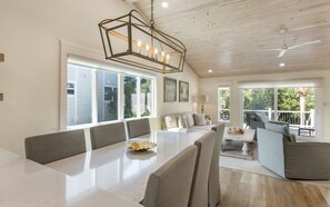 Enjoy meals in this dining area with a long table and comfortable seating, surrounded by large windows offering views of the surrounding greenery.