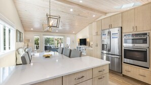 Een moderne keuken met een groot eiland, roestvrijstalen apparatuur en licht houten kasten.