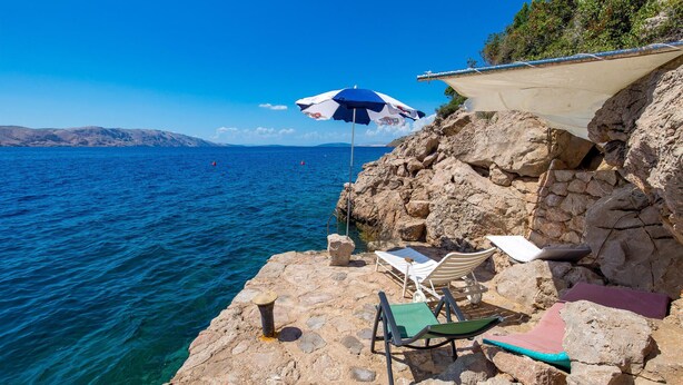 A rocky seaside with a clear blue sea, a beach umbrella, and a lounge chair. - 2 bedroom cozy home in Josinovac (Josinovac)