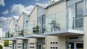 A modern building with numbered balconies, a reception area, and glass railings. - V Motel (Christchurch)