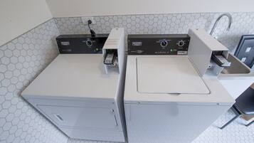 A laundry area with two front-loading washing machines and a dryer, equipped with control panels and a power cord.