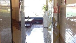 A hotel lobby with a reception desk, a seating area, and a view of the outdoors. - Thiên Các 2 (Quy Nhon)