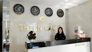 A reception desk with clocks displaying Tokyo, Paris, and New York times, and a decorative sign with "THIEN CAc". - Thiên Các 2 (Quy Nhon)