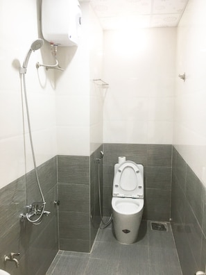 A small, modern bathroom with a toilet, a shower, and a hand dryer. - Thiên Các 2 (Quy Nhon)