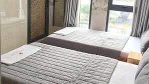 A hotel room with two beds, a TV, and a window with curtains. - Thiên Các 2 (Quy Nhon)