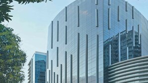 A modern building with a curved glass facade and vertical lines, surrounded by trees and a clear sky. - 8 Newtown Boulevard by SIET (Lapu-Lapu)
