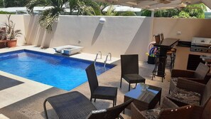 Ein Poolbereich mit Pool, Liegestühlen, einem Grill und einem Tisch.
