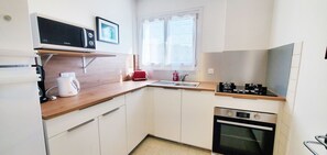 A compact kitchen with white cabinets, a microwave, a toaster, a kettle, and a small oven.