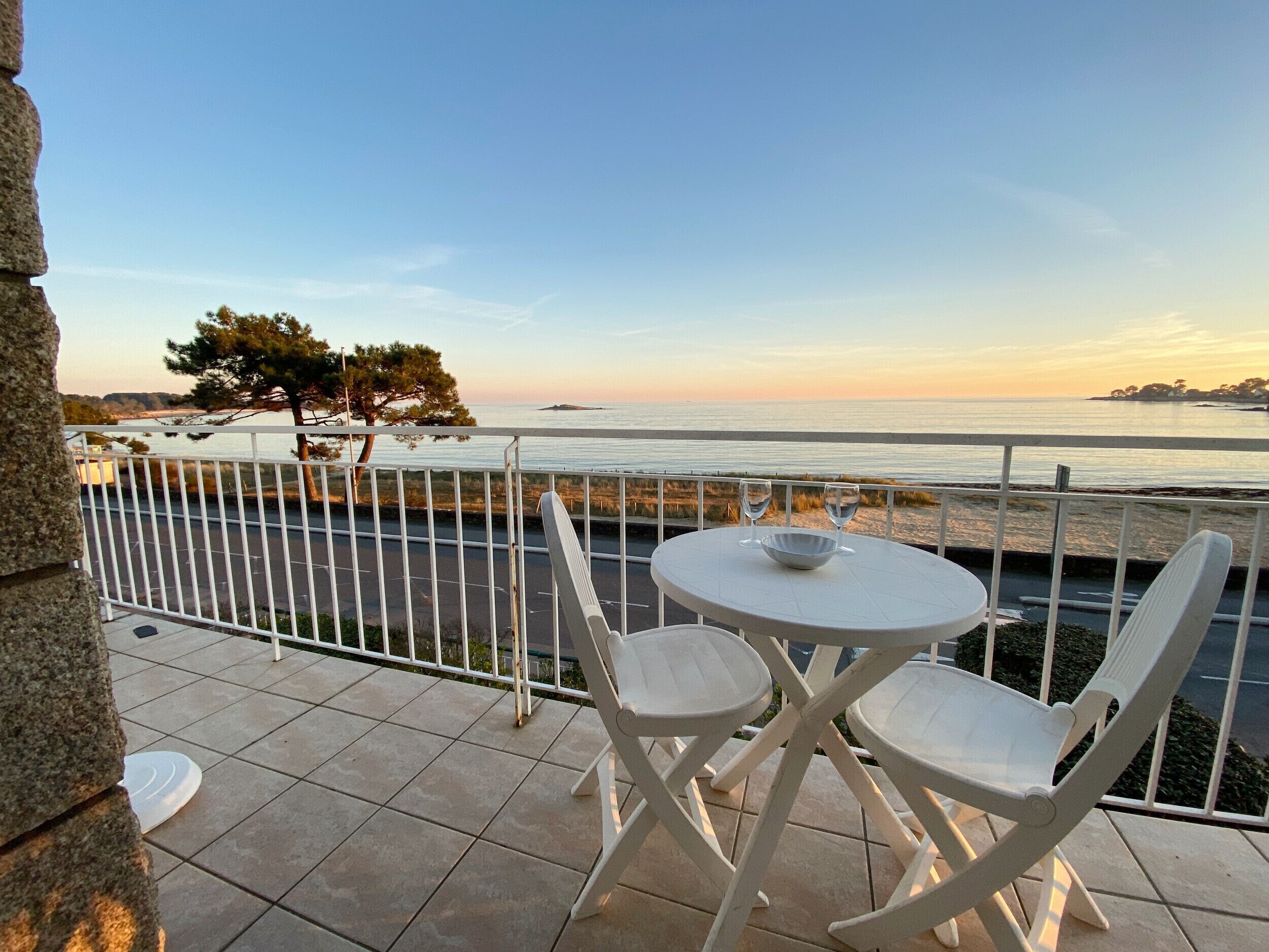 Een terras met een tafel en stoelen met uitzicht op een strand en de zee.