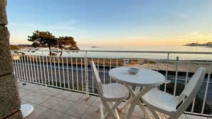 En terrasse med et bord og stole med udsigt over en strand og havet.