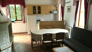 Un espacio habitable compacto con una mesa de comedor, sillas, sofá y una zona de cocina con armarios y un refrigerador.