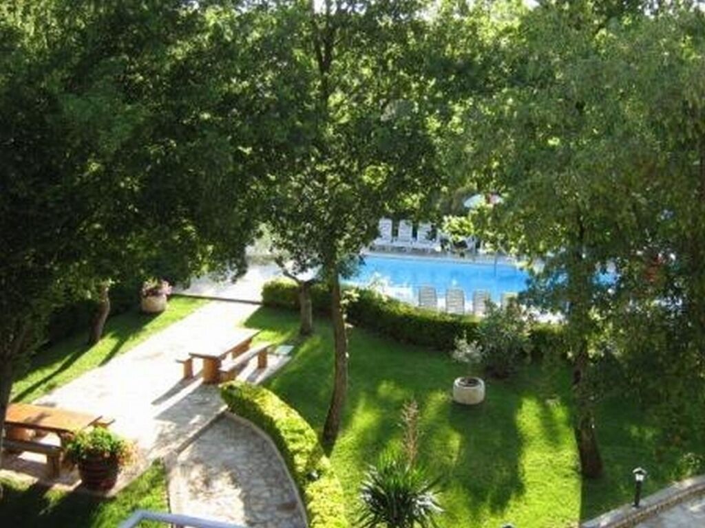 A lush garden with a pool, benches, and a clear view of the pool.