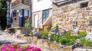 A stone building with a garden in front, featuring colorful flowers and a rustic stone wall.