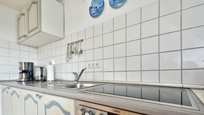 A modern kitchen with white tiles, stainless steel appliances, and wooden cabinets.
