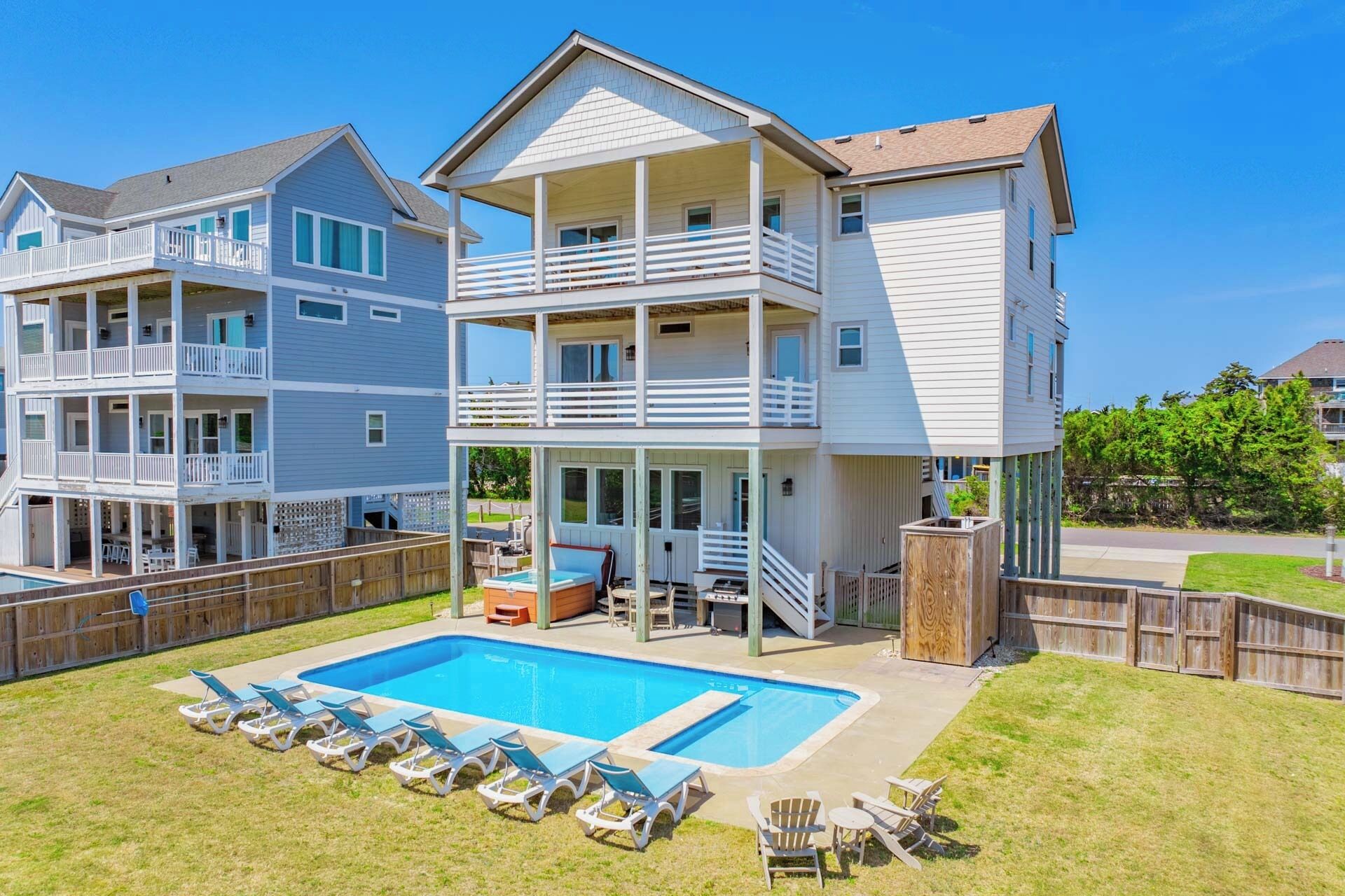 A two-story residential building with a balcony, a swimming pool, and outdoor seating.