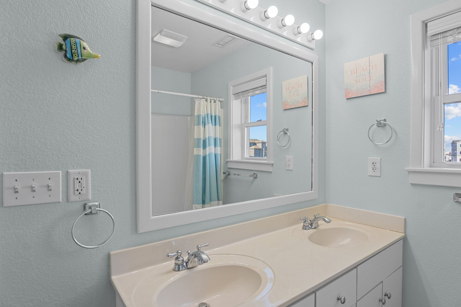 A bathroom with two sinks, a large mirror, and a shower curtain.