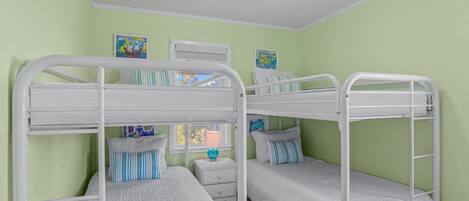 A bunk bed room with a white metal frame, green walls, and a window with a view.