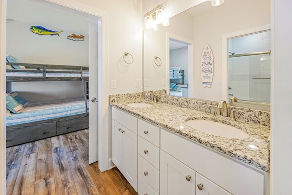 Une salle de bain avec deux lavabos, un grand miroir et une décoration sur le thème du surf.