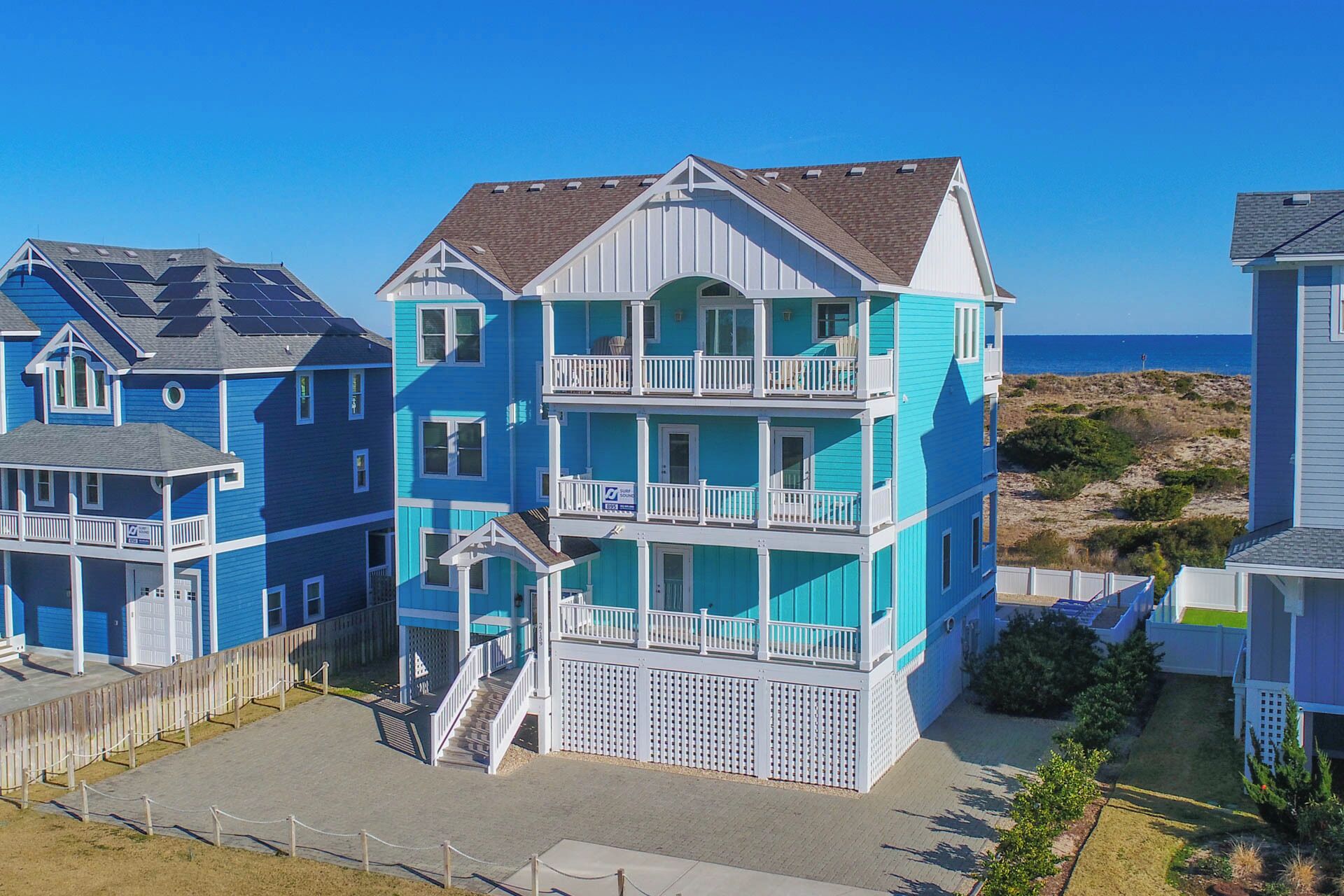 A multi-story beachfront building with balconies, a staircase, and a view of the ocean.