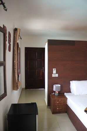 Cozy retreat with a neatly made bed, wooden headboard, and a convenient nightstand with a lamp.