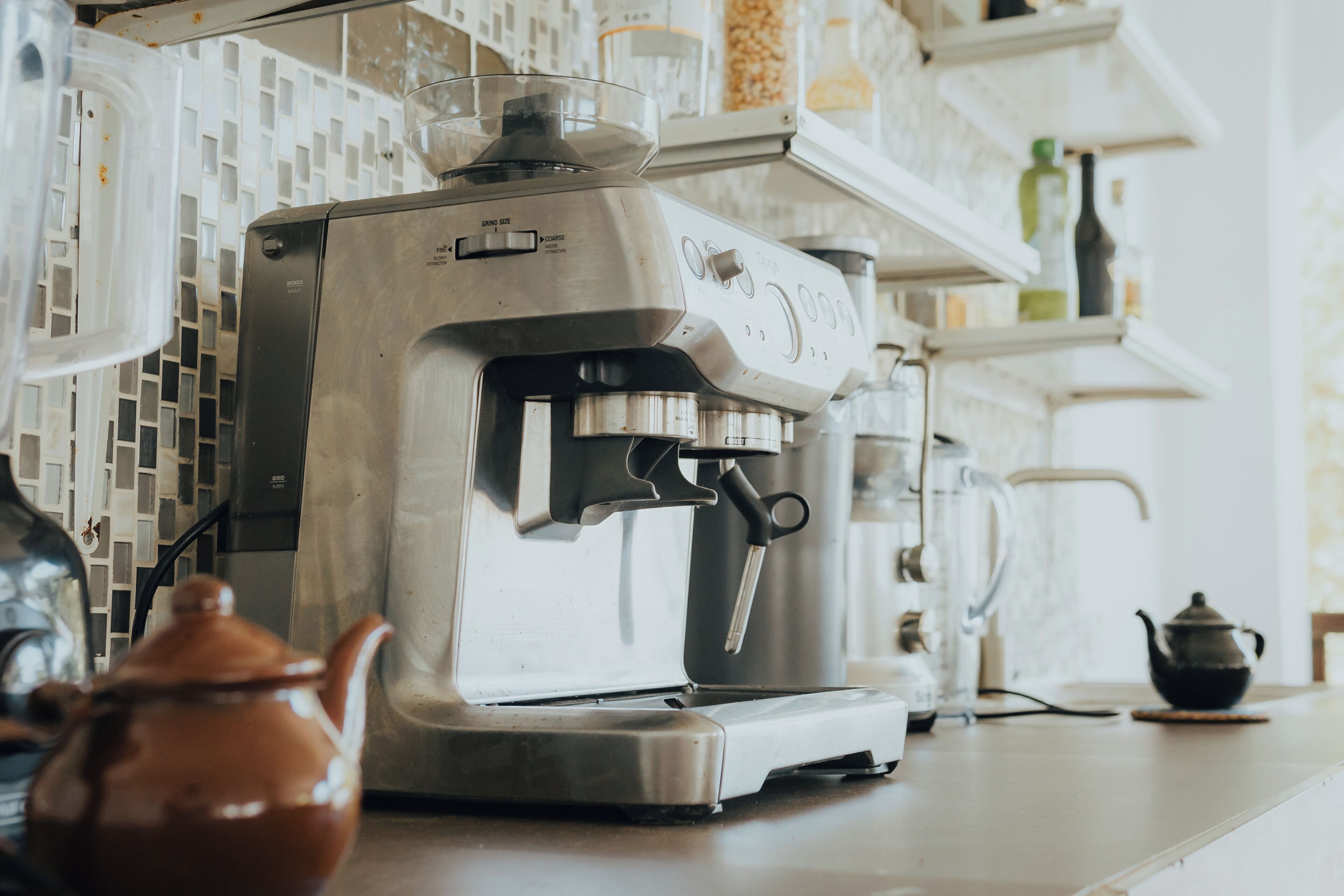 Una cafetera sobre una encimera de cocina, con una tetera cerca.