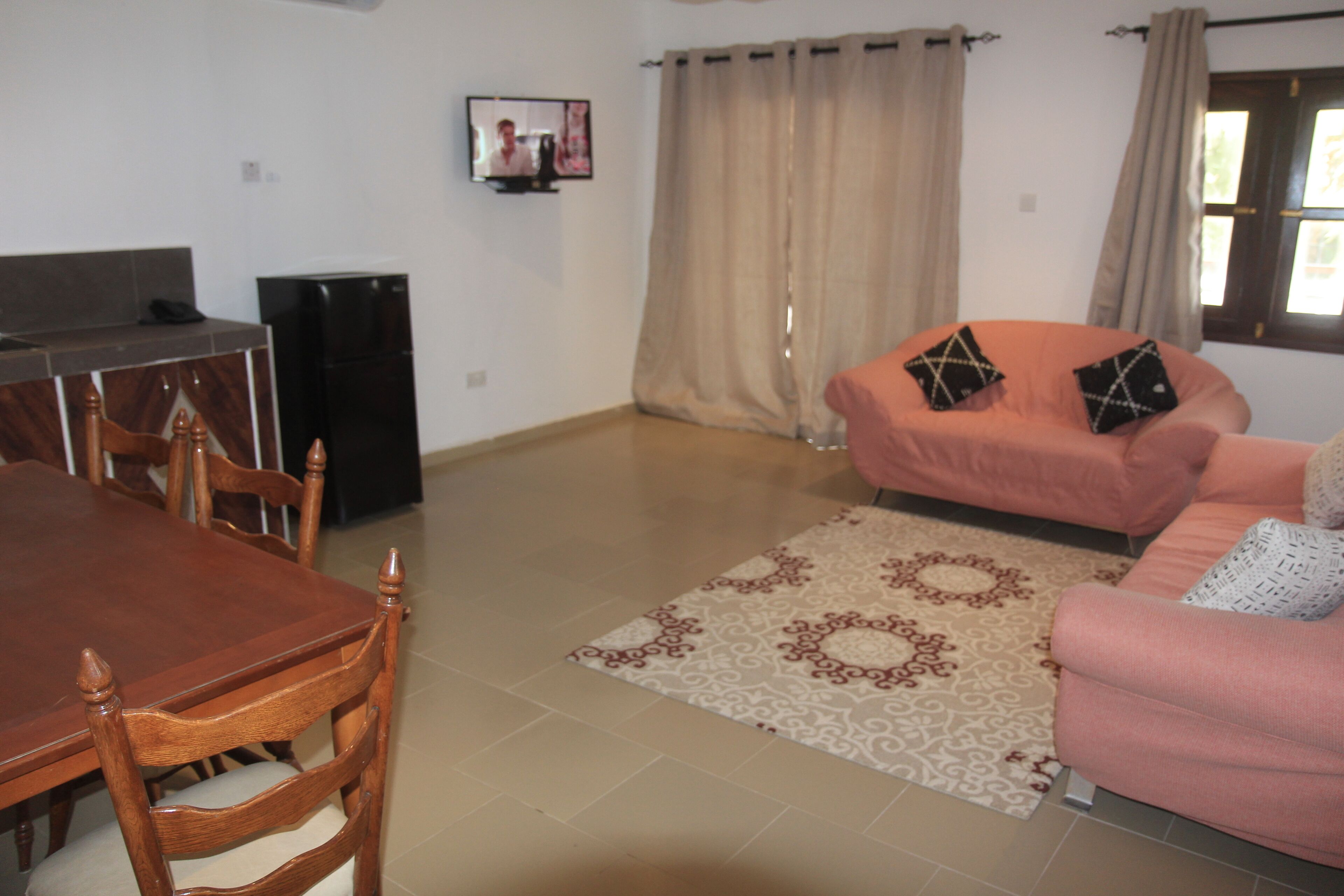 A living room with a dining table, chairs, a sofa, and a television.