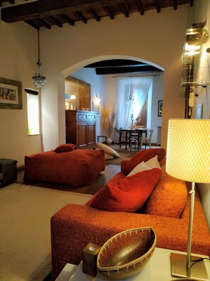Una sala de estar acogedora con un conjunto de sofás, un comedor y una cocina al fondo.