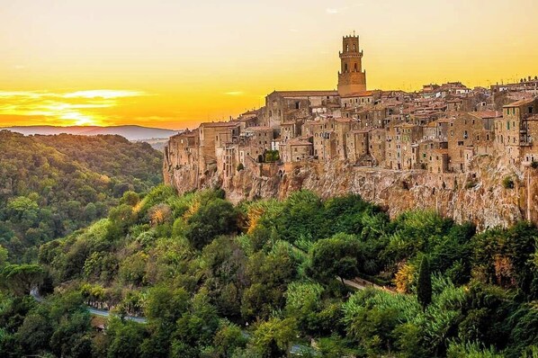 Un pueblo histórico con una torre destacada, abundante vegetación y un acantilado escarpado.