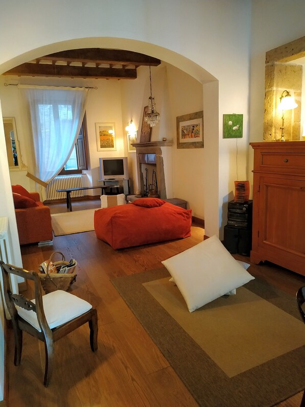 A cozy living room with a fireplace, a television, and a red sofa. - Environment for relaxation, ideal for nature-loving couples. (Pitigliano)