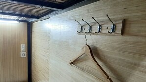 A wooden wall with a wooden hanger and four metal hooks. - Chiasti Capsule Hostel - Adults Only (Cebu City)