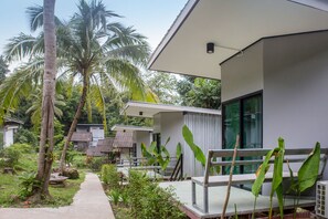 A modern building with a concrete pathway leading to a wooden bench. - Wave-F Homestay (Ko Kood)