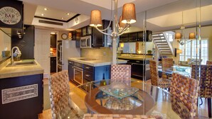 Une cuisine moderne dotée d’un îlot central, d’un coin repas avec une table en verre et d’un bar agrémenté d’une enseigne.