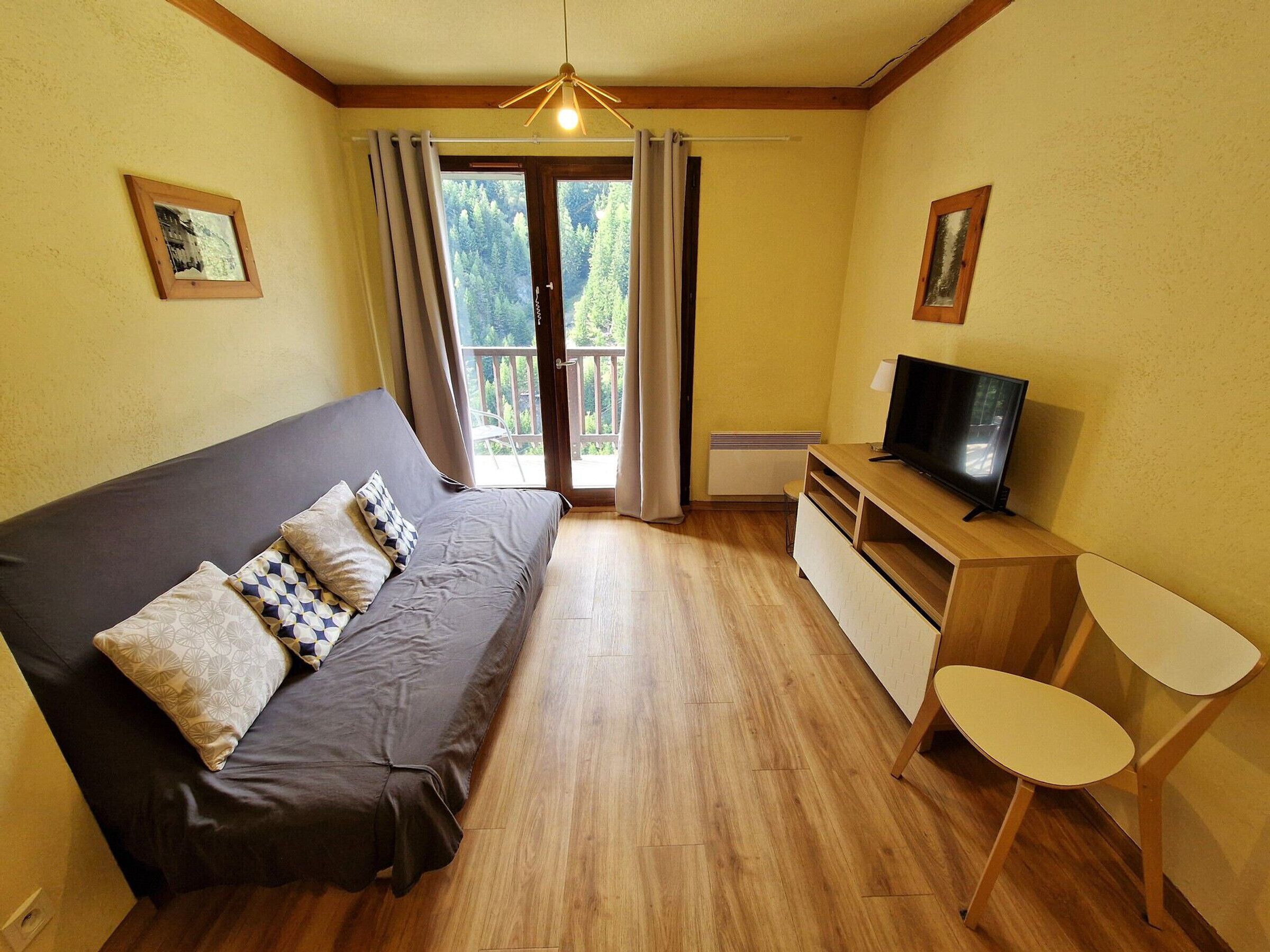A cozy room with a sofa, a TV, and a small table.