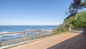 Eine Holzterrasse mit Geländer, mit Blick auf einen Strand.