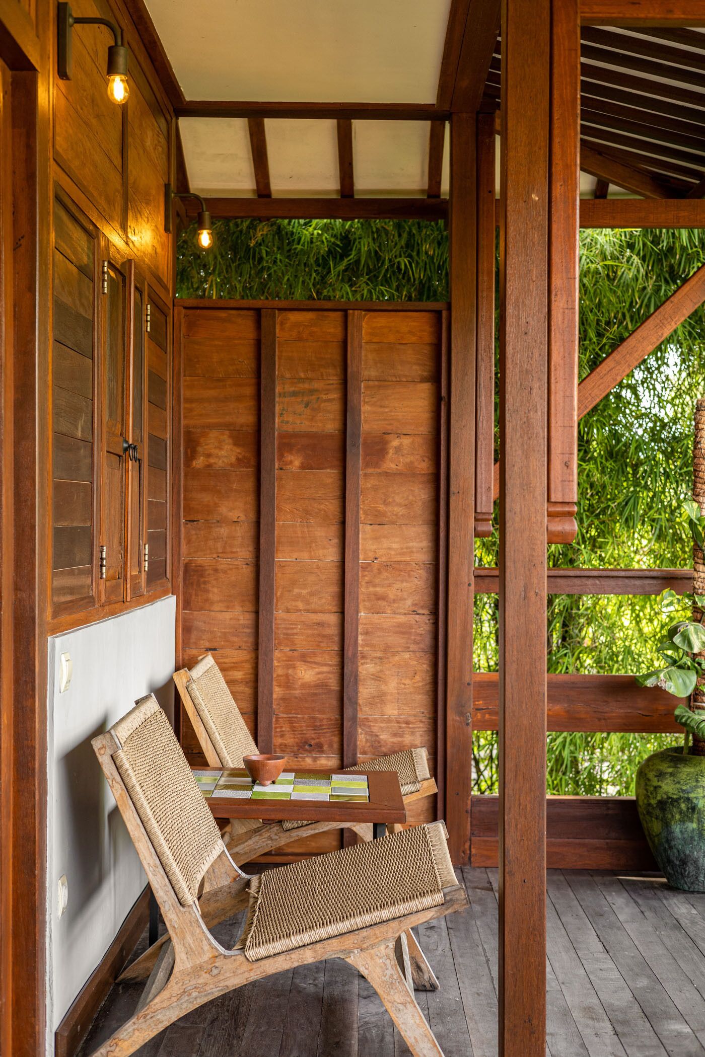 A wooden deck with a table and chairs, surrounded by wooden walls and a glass door.