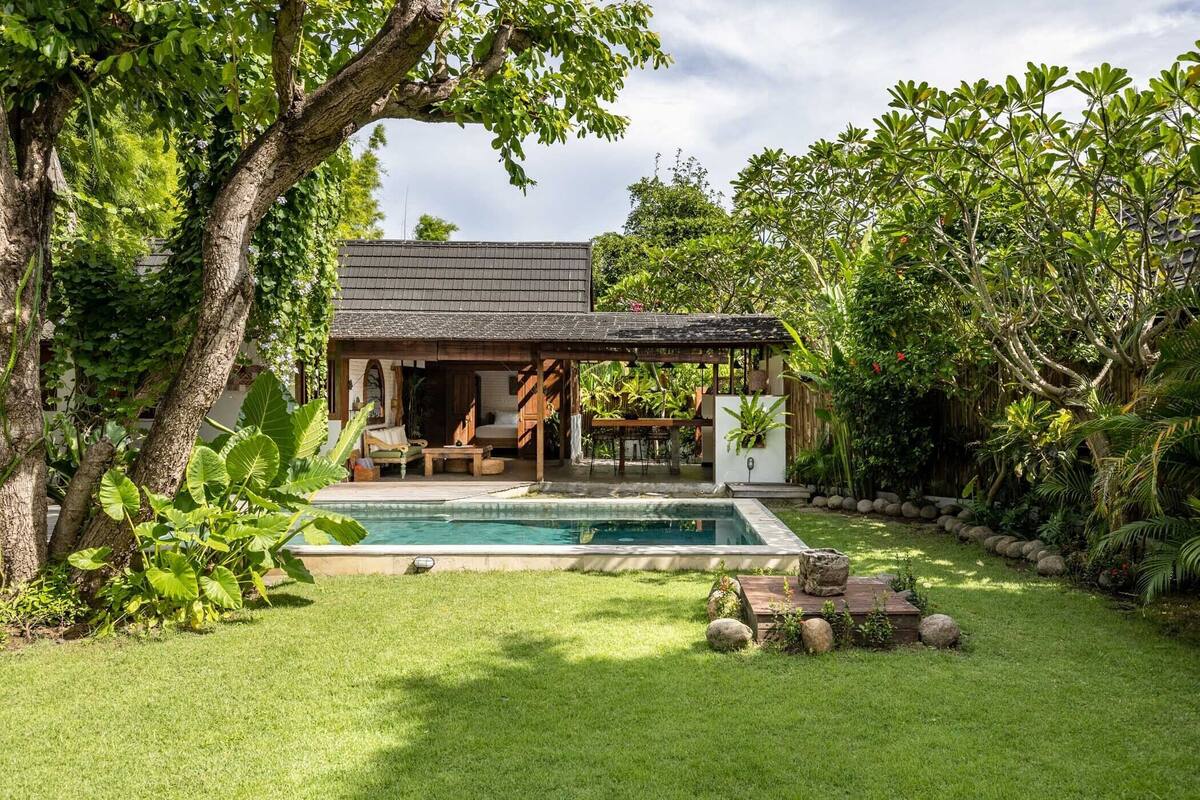 A house with a swimming pool, surrounded by lush greenery and trees.