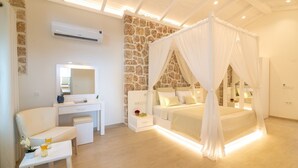 A bedroom with a stone wall, a white bed with a canopy, a desk with a mirror, and a chair.