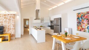 A modern kitchen with white cabinetry, a central island, and a dining area with a wooden table and white chairs.