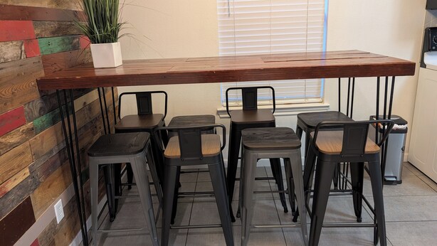 A dining area with a long wooden table and six black stools. - The Discerning Minimalist House in the Heart of Dallas (Dallas)