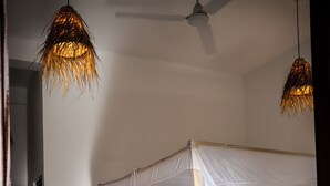 A room with a four-poster bed, a ceiling fan, and two hanging light fixtures. - Surf & Relax Inn Arugambay (Arugam Bay)