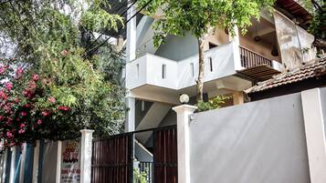 A multi-story building with balconies, a gated entrance, and a sign for 'Surf & Relax' rooms.