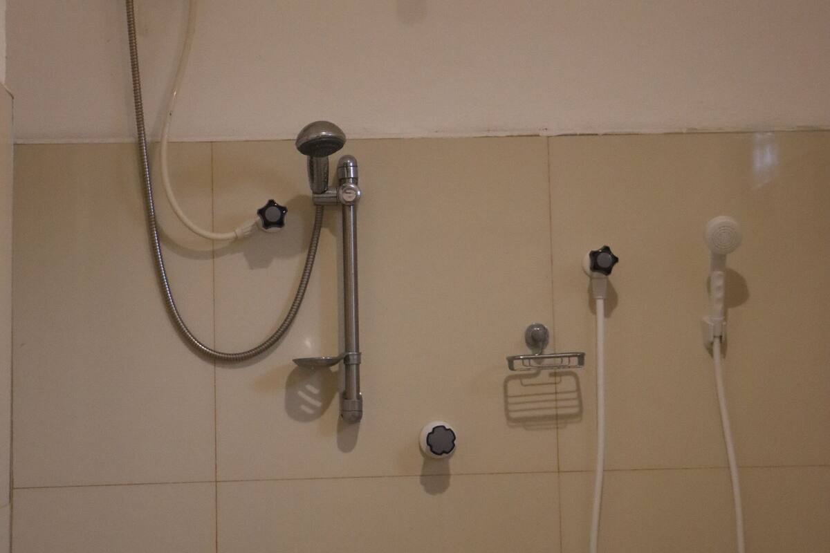 Un baño con ducha empotrada, cabezal de ducha de mano, grifo de mano y un perchero para toallas.