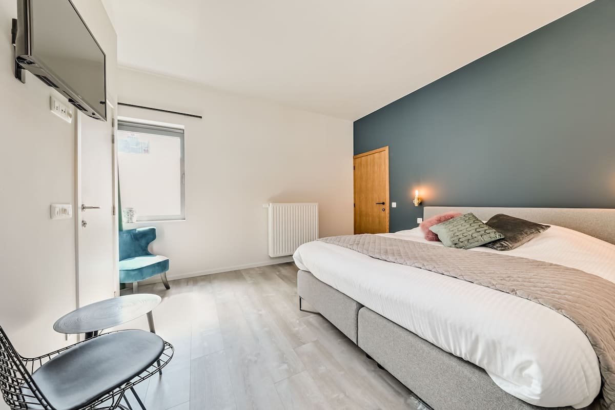 A modern bedroom with a large bed, a desk, and a chair.