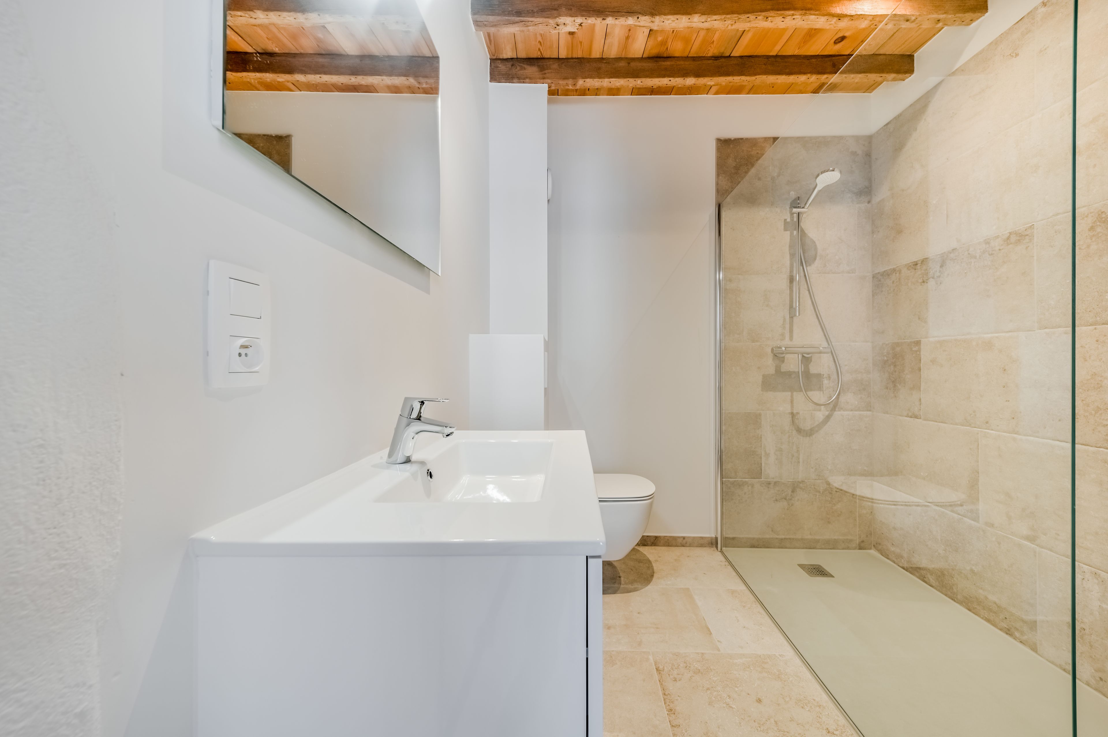 A modern bathroom with a white sink, a toilet, and a glass-enclosed shower area.