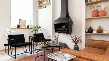 A modern living room with a black fireplace, black and brown furniture, and decorative items on shelves.